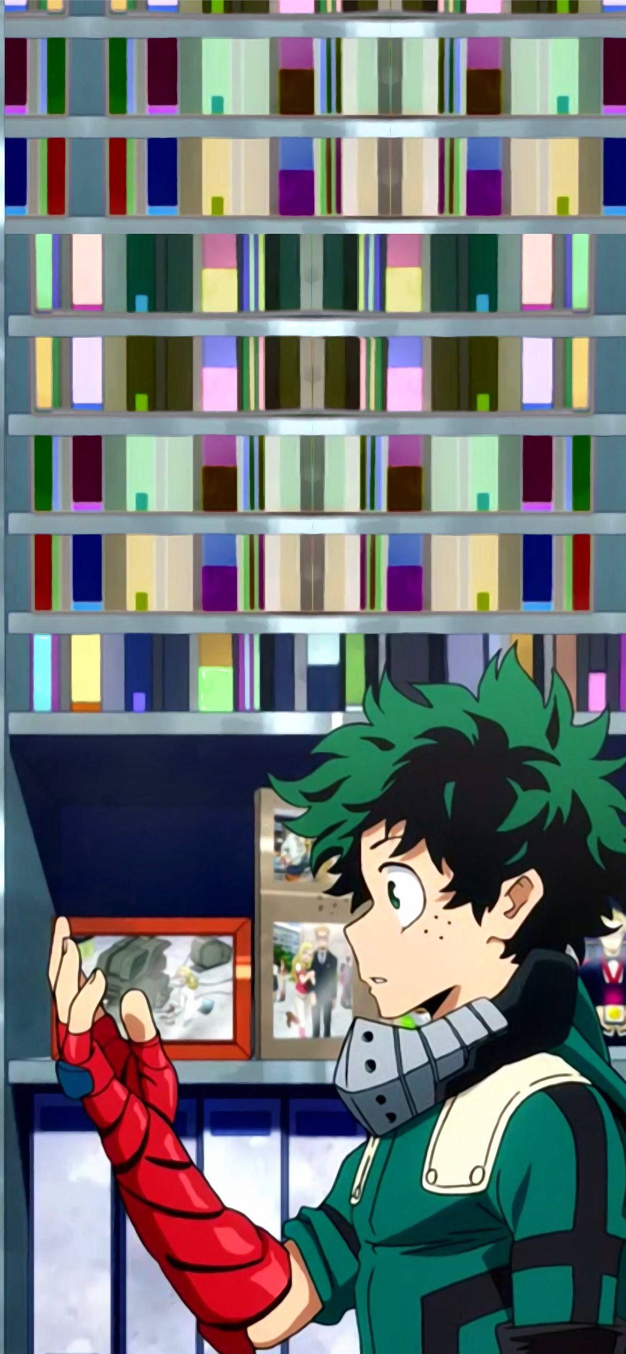 Deku Cute 桌布 壁紙 — 一位綠髮動漫英雄穿著紅綠套裝，凝視著一張裱框照片，站在一個裝滿彩色書籍的高聳書架前。