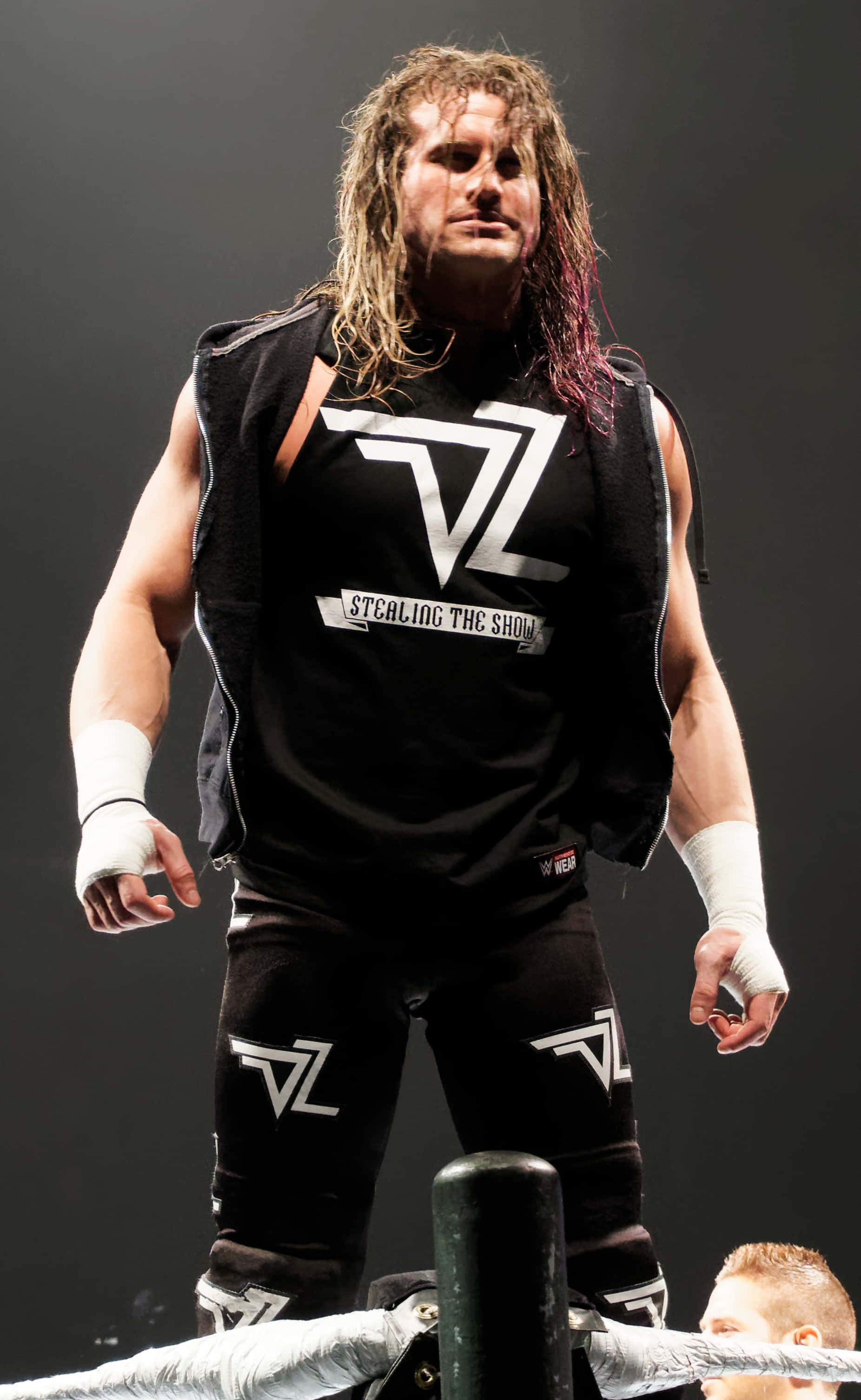 Dolph Ziggler, Renowned WWE Champion in Action 壁紙 — 一位肌肉發達、長著長波浪髮的摔角手，身穿帶有白色 'ZL' 標誌和 'STEALING THE SHOW' 文字的黑色裝備，站在摔角擂台上。