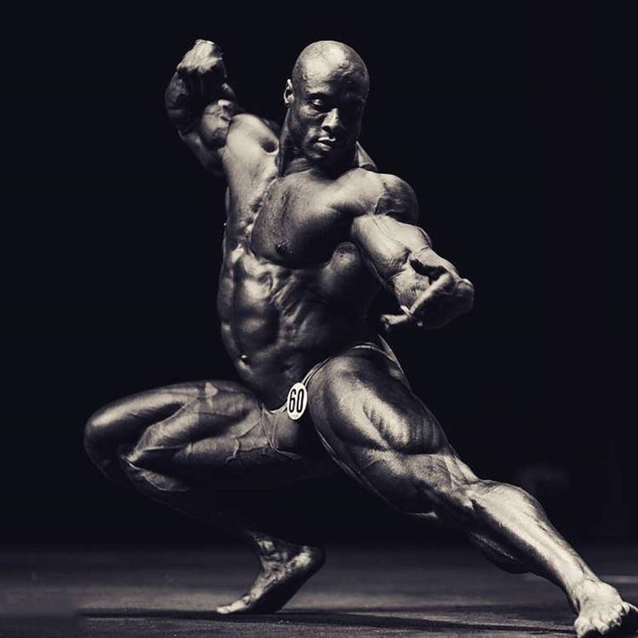 Exercise 桌布 壁紙 — 一位肌肉發達的健美運動員在黑色背景前，於戲劇性的工作室燈光下擺出強而有力的姿勢。