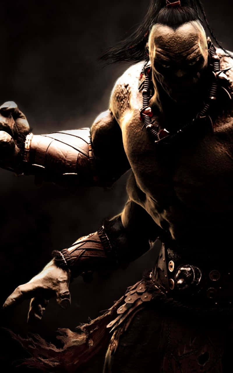 Mortal Kombat Goro 桌布 壁紙 — 一位肌肉發達的戰士，身上有部落紋身和皮革盔甲，在黑暗煙霧繚繞的環境中向前衝刺。