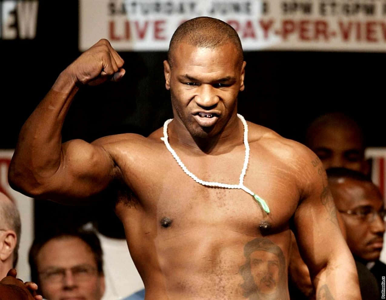 mike tyson 桌布 壁紙 — 一位肌肉發達的拳擊手在稱重活動中，戴著白色珠串項鍊，表情兇狠地彎曲二頭肌。