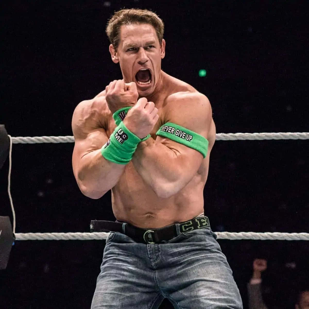 John Cena 桌布 壁紙 — 一位肌肉發達的摔角手在擂台上握緊拳頭咆哮，戴著寫有「never give up」的綠色腕帶。
