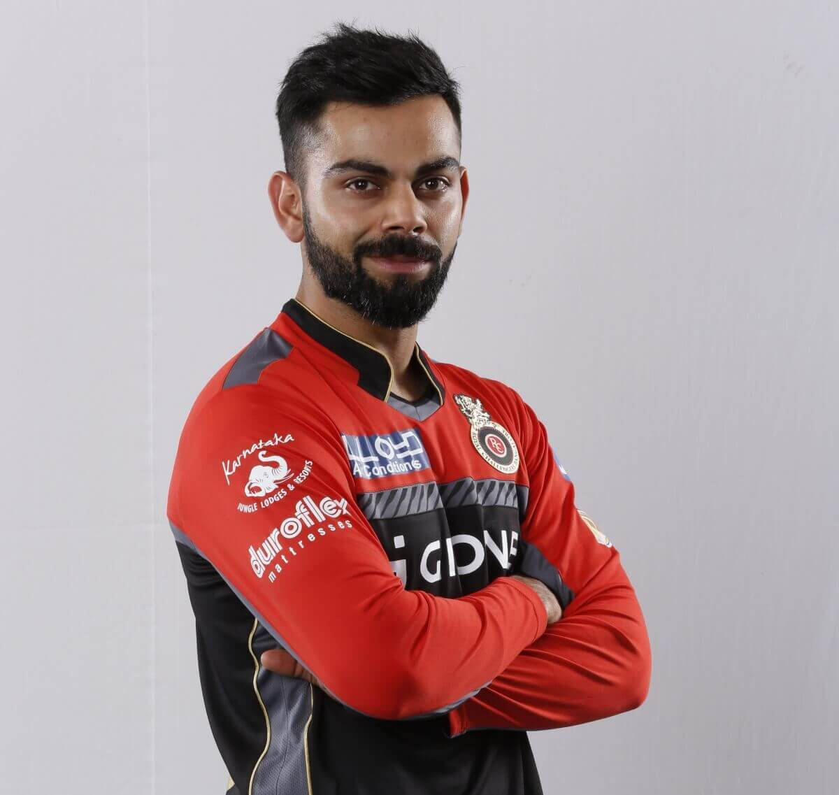royal challengers bangalore 桌布 壁紙 — 一位自信嘅板球球員，身穿紅黑球衣，雙手交叉企喺純白背景前。