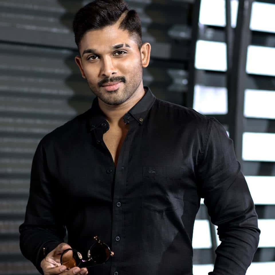 Allu Arjun 桌布 壁紙 — 一位自信嘅男人著住黑色恤衫，喺現代幾何背景前揸住太陽眼鏡。