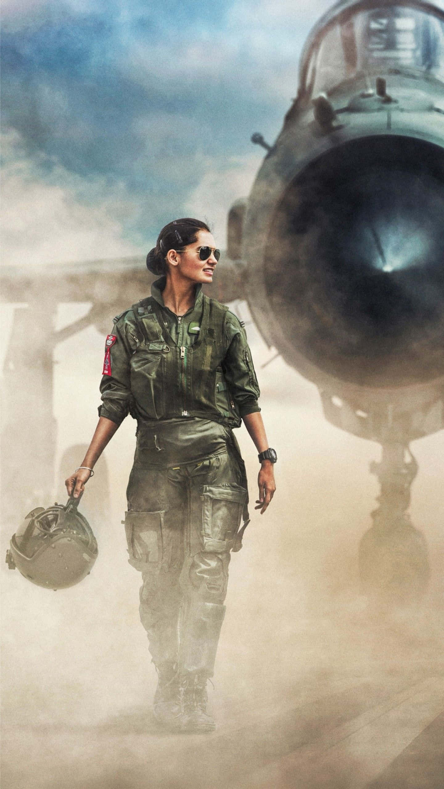 Indian Army 桌布 壁紙 — 一位自信的女戰鬥機飛行員穿著綠色飛行裝備，在多雲的天空下，在塵霧中走向她的噴射機。