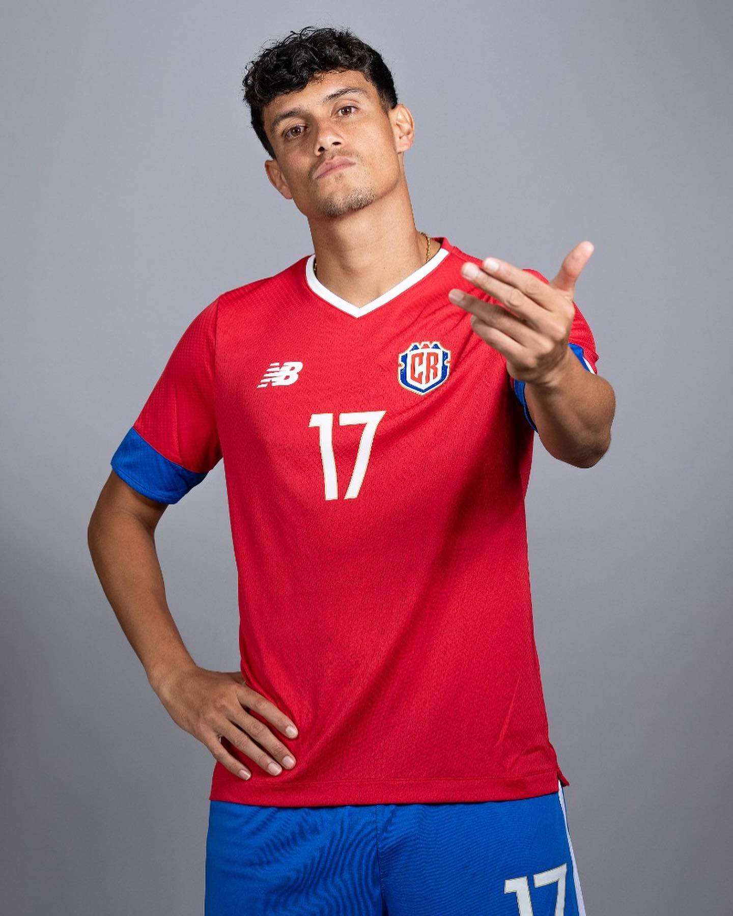 Football Players 桌布 壁紙 — 一位自信的足球運動員身穿紅色球衣，號碼17，在純灰色工作室背景前擺姿勢。