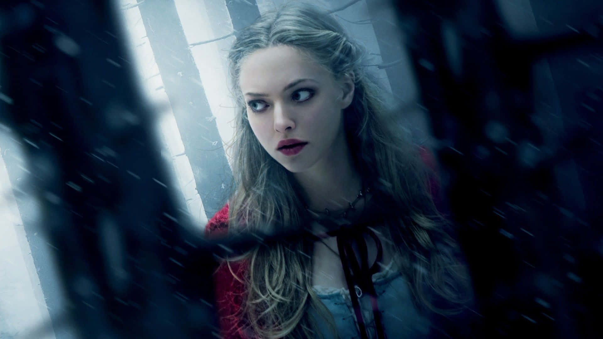 Amanda Seyfried 桌布 壁紙 — 一位蒼白的長金髮女子在昏暗、積雪的都市小巷中，透過被雨水打濕的窗戶凝視著。