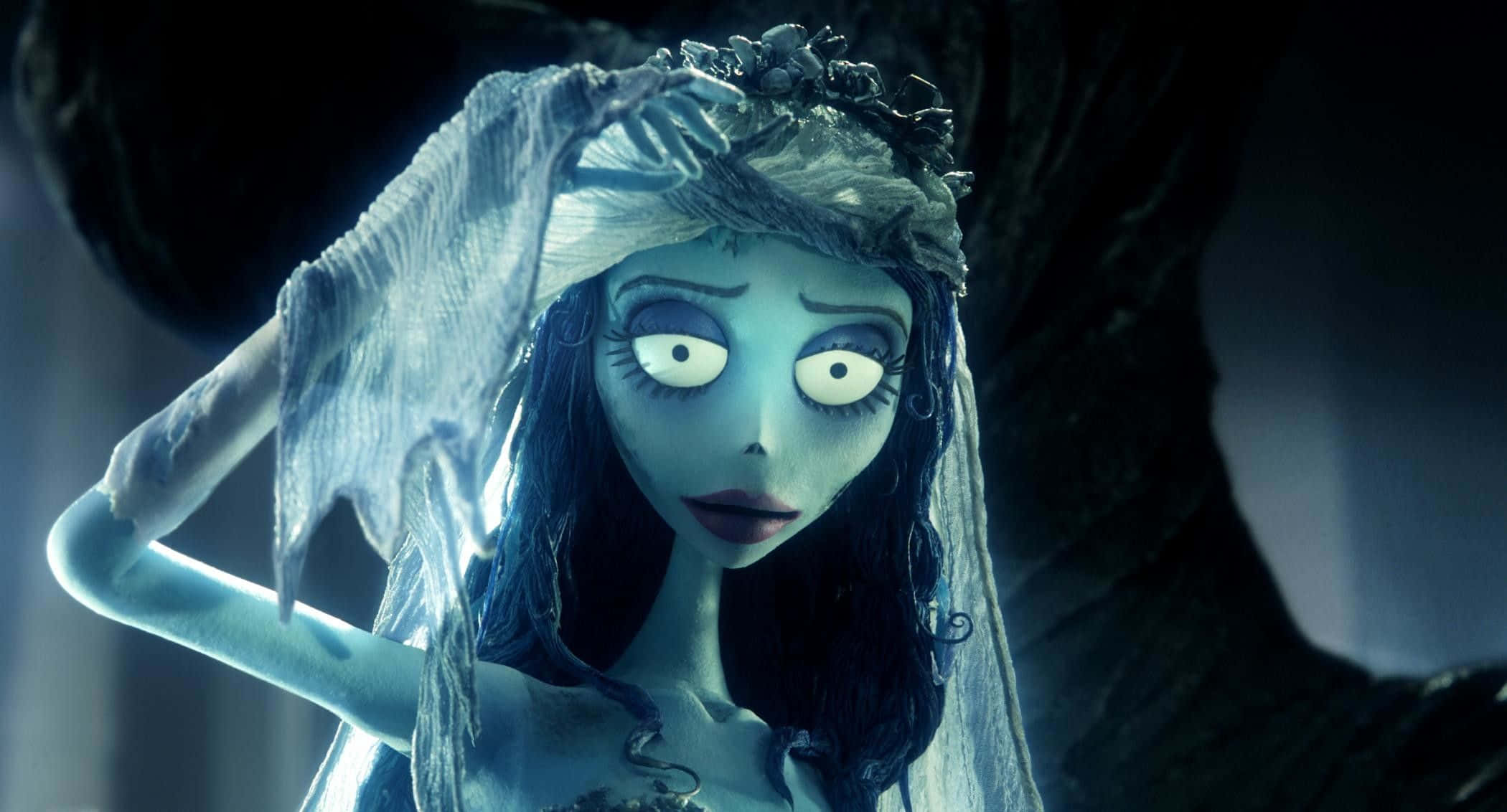 corpse bride 桌布 壁紙 — 一位蒼白藍皮膚的新娘，睜大眼睛，披著破爛的面紗，站在陰影的憂鬱中，在詭異的寂靜中抓著自己的頭。