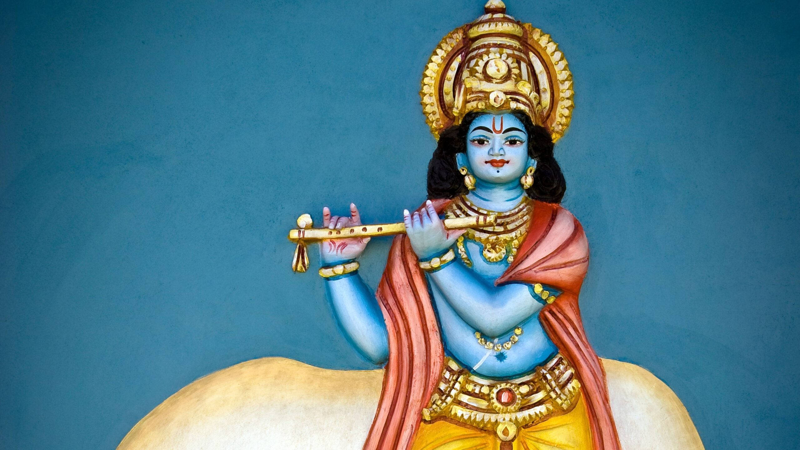 Krishna HD 桌布 壁紙 — 一位藍皮膚的神祇戴著金色皇冠和珠寶，坐在一頭白牛上吹奏長笛，背景為純藍色。