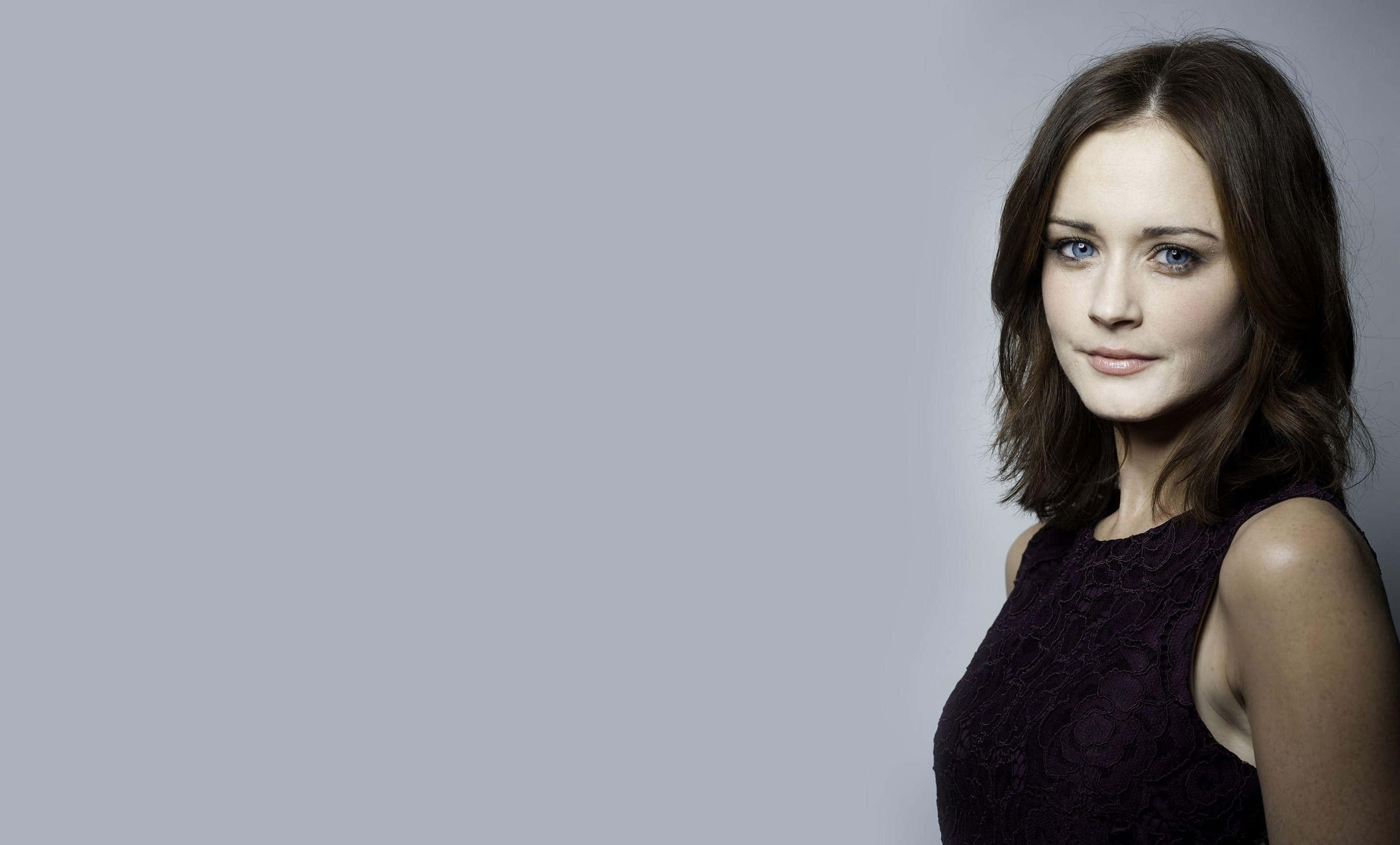 Alexis Bledel 桌布 壁紙 — 一位藍眼睛、深色頭髮的女性，在純灰色背景前穿著黑色蕾絲上衣。