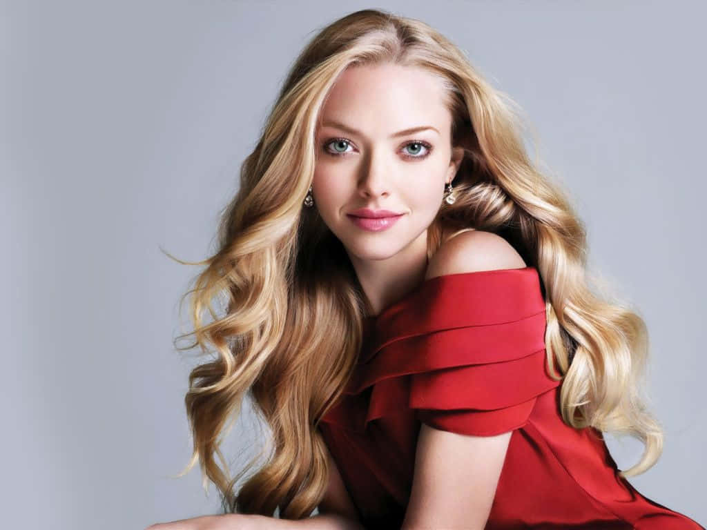 Amanda Seyfried 桌布 壁紙 — 一位藍眼金髮女性穿著紅色露肩連衣裙，背景為純灰色。