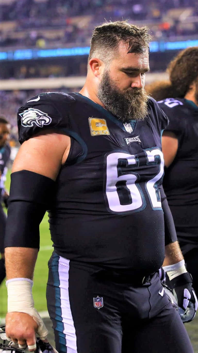 Jason Kelce 桌布 壁紙 — 一位費城老鷹隊的足球員，留著濃密鬍鬚，穿著62號球衣，在球場燈光下離開球場。