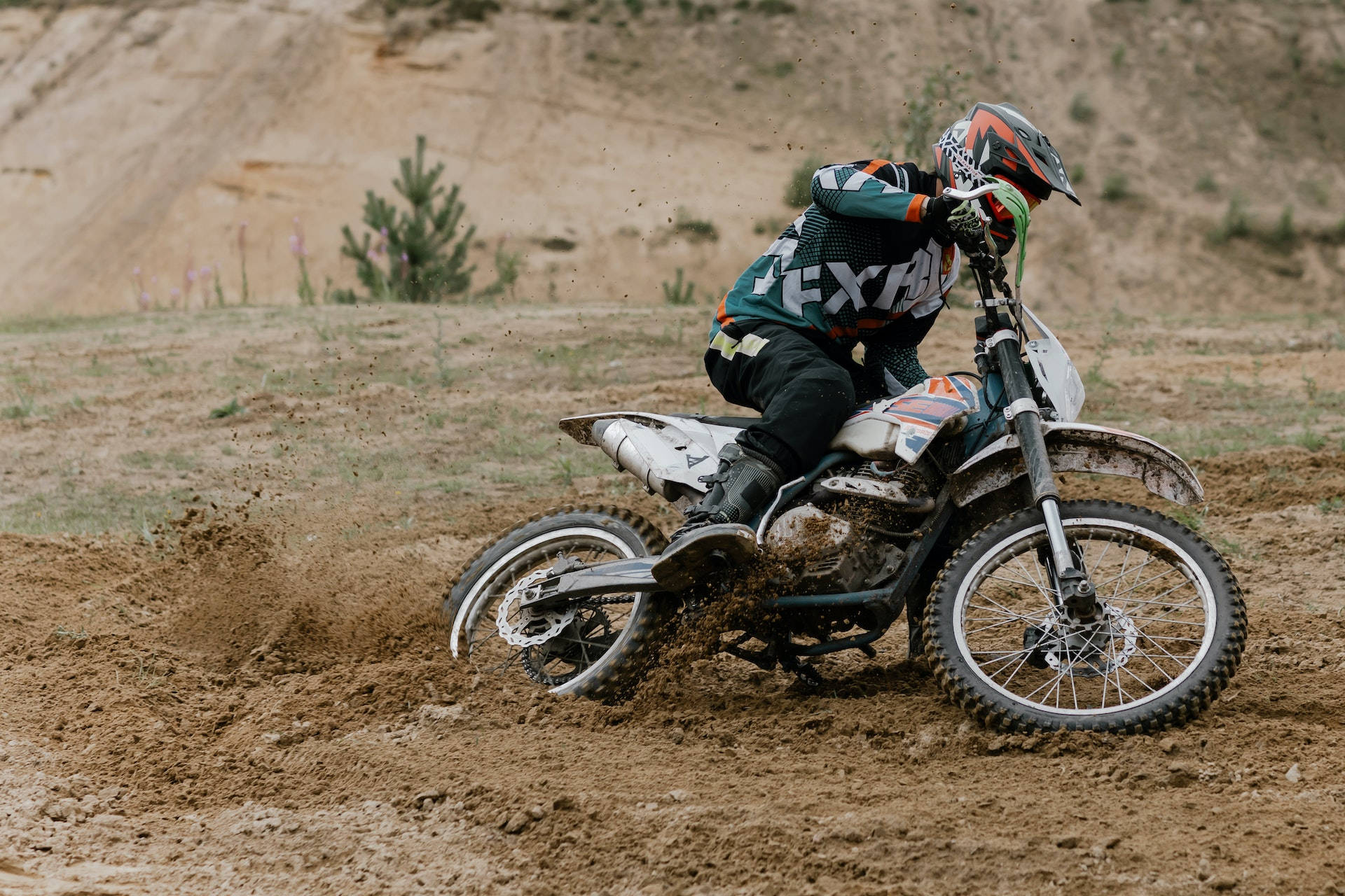Motocross 桌布 壁紙 — 一位越野電單車手在乾燥草地上騎著越野電單車轉彎時濺起泥漿。