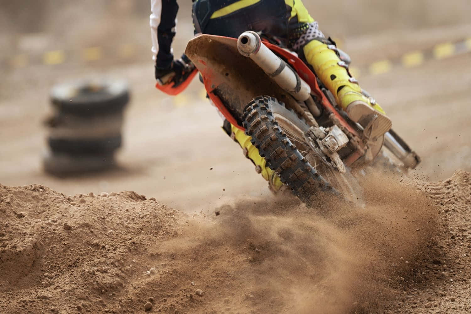 Dirtbike 桌布 壁紙 — 一位越野電單車手在崎嶇的越野賽道上傾斜入急彎，揚起泥土。