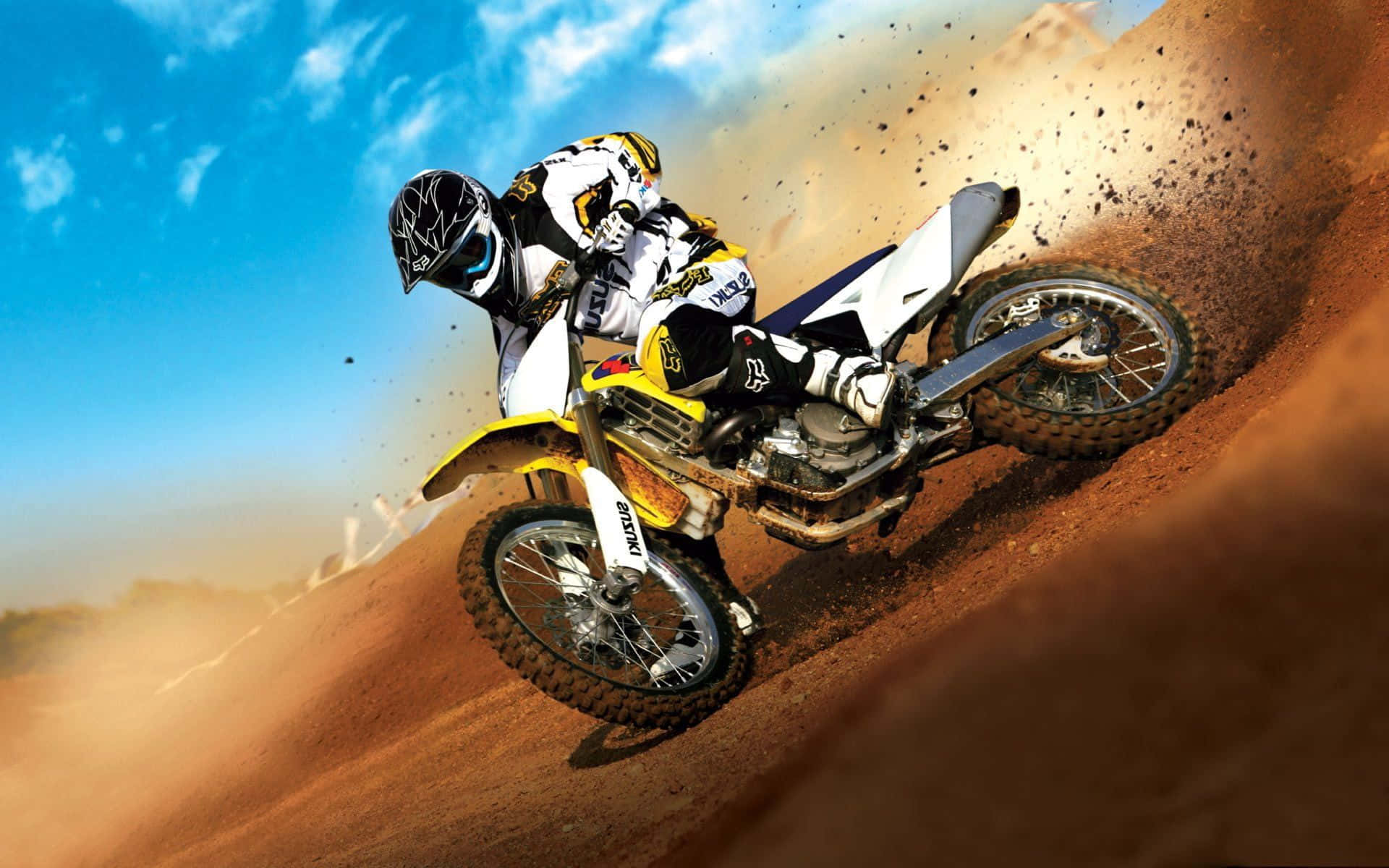 Motocross 桌布 壁紙 — 一位越野電單車手在泥地賽道上傾斜入急彎，在明亮的藍天下揚起一片塵土。