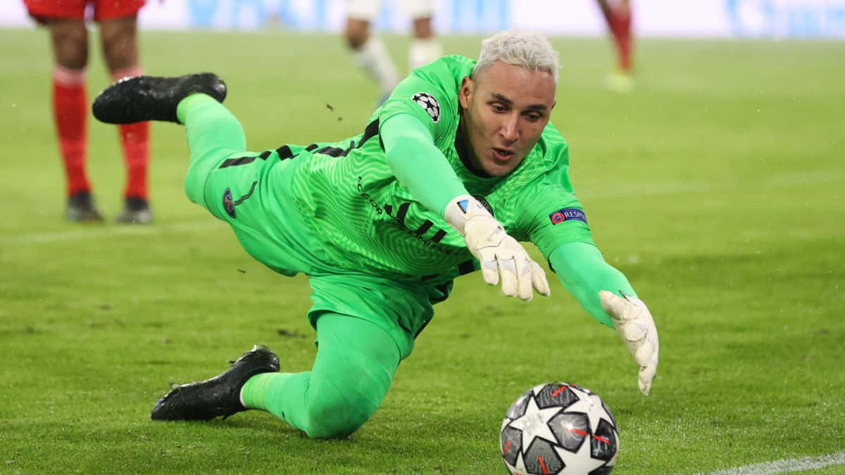 Keylor Navas 桌布 壁紙 — 一位身穿亮綠色球衣的足球守門員在充滿活力的綠色球場上低身撲救，阻止歐聯比賽用球。