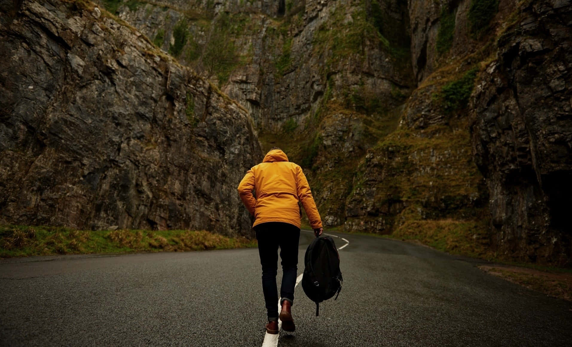 Hiking 桌布 壁紙 — 一位身穿亮黃色外套的孤獨旅人，沿著蜿蜒的山路行走，兩旁是高聳的岩石峭壁。