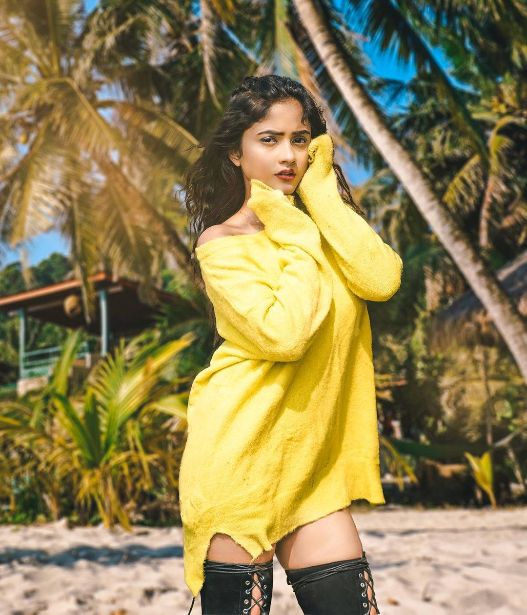 Nisha 桌布 壁紙 — 一位身穿亮黃色露肩毛衣的女性站在沙灘上，棕櫚樹在清澈的藍天下搖曳。