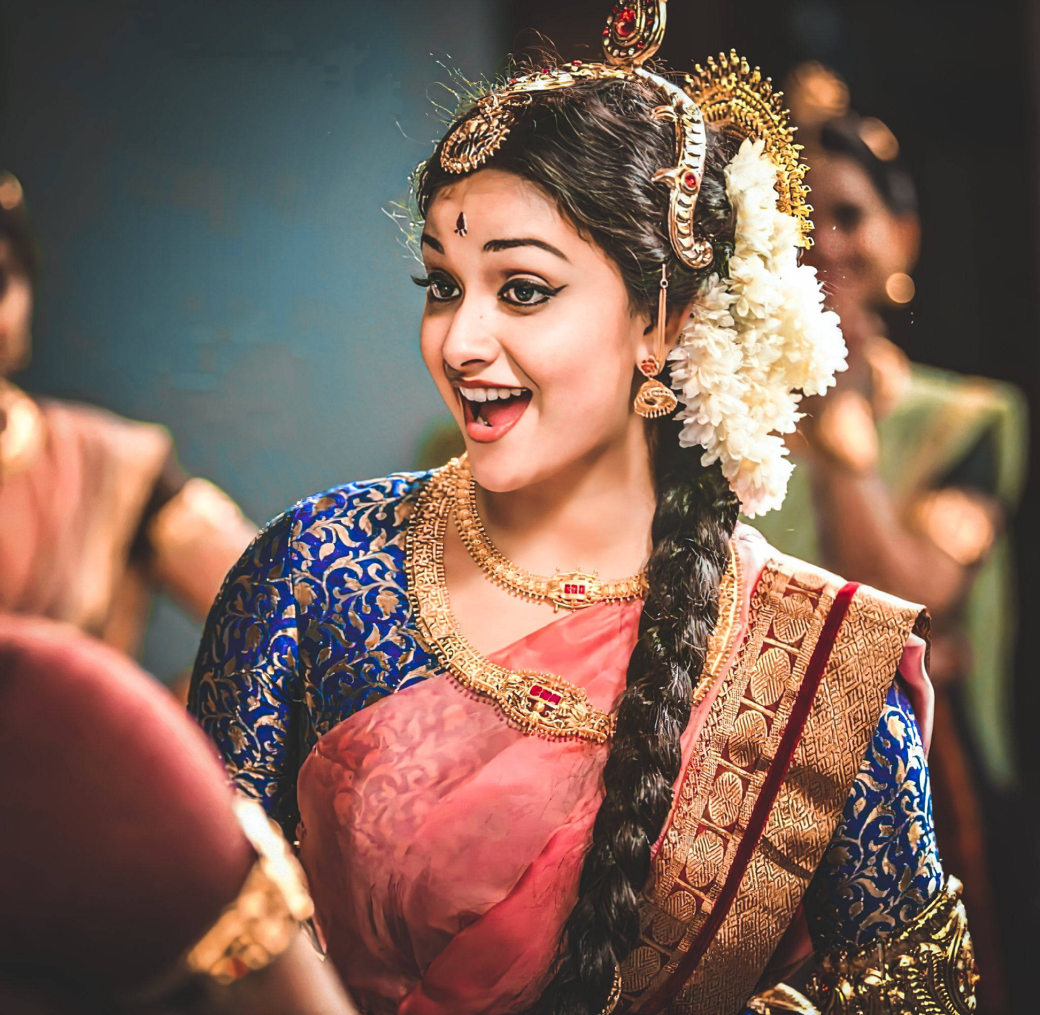 Tamil Actors HD 桌布 壁紙 — 一位身穿傳統印度服飾、光彩照人的女性，佩戴著黃金首飾和白色花環，露出喜悅的笑容。
