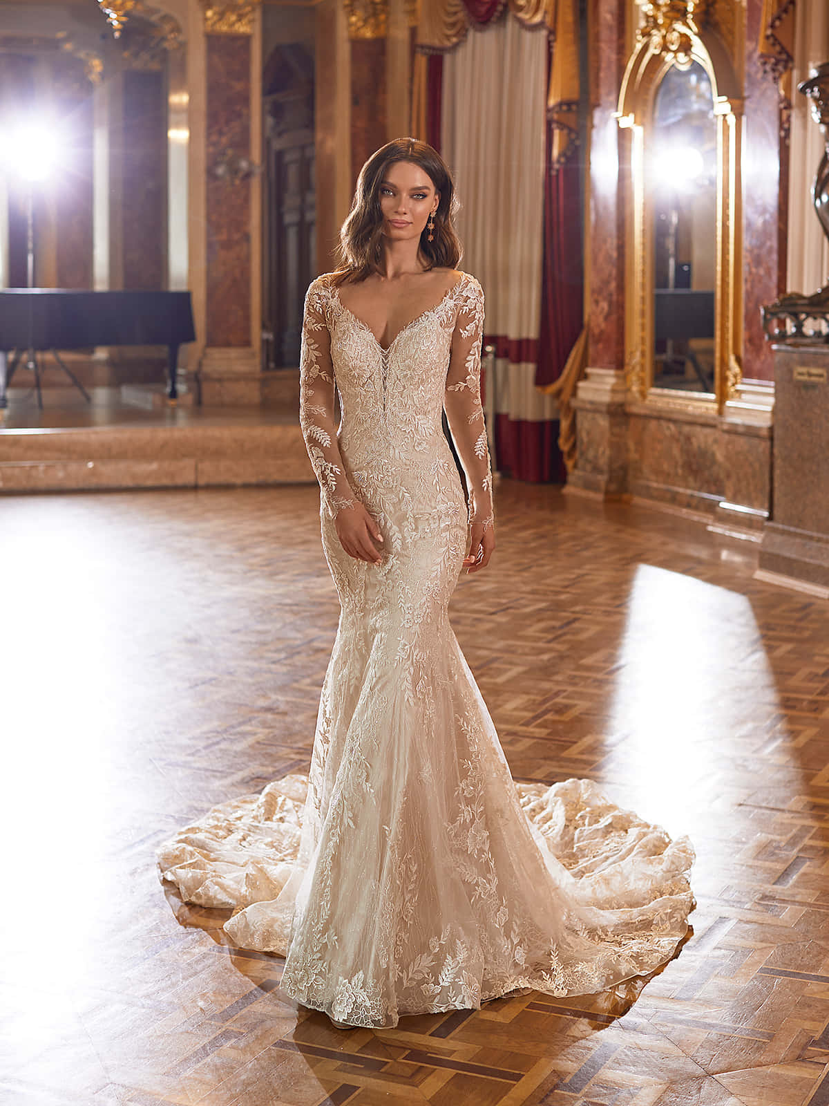 Bride's Dress 桌布 壁紙 — 一位身穿優雅奶油色蕾絲美人魚禮服的女士，站在鋪有大理石地板和金色裝飾的宏偉華麗舞廳中。