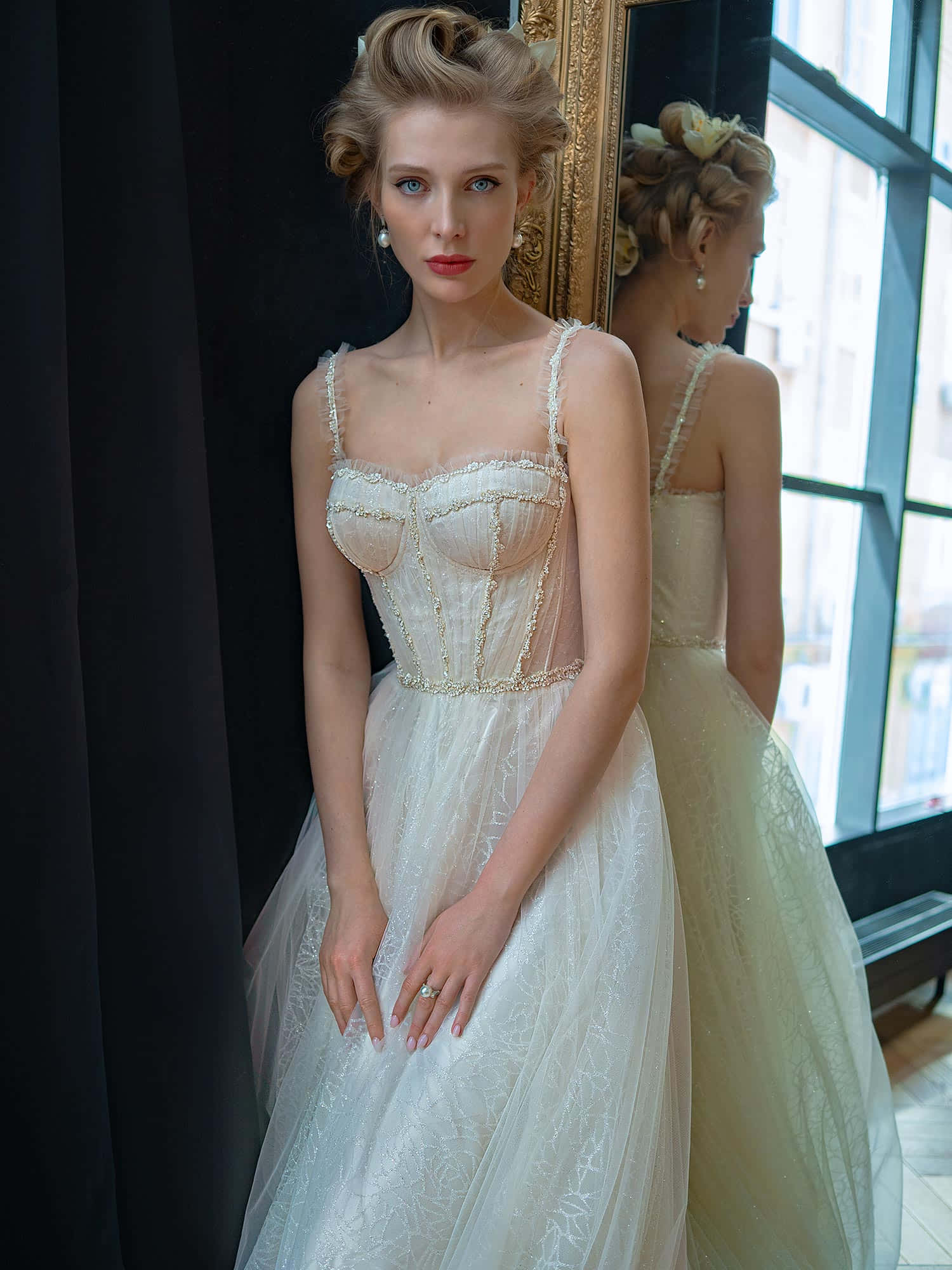Wedding Dress 桌布 壁紙 — 一位身穿優雅象牙色禮服、搭配珠飾緊身胸衣的女性，站在鏡子前，陽光灑滿房間，鏡中映出她的身影。