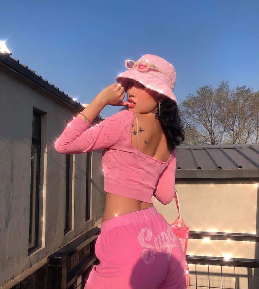 Pink Fashion 桌布 壁紙 — 一位身穿全粉紅色服裝和漁夫帽的年輕女子在藍天白雲下的陽台上擺姿勢。