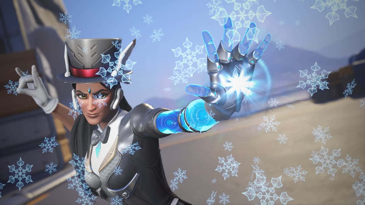 Overwatch Symmetra 桌布 壁紙 — 一位身穿冬季裝備的女性英雄施展閃耀的藍色冰系法術，雪花在她伸出的手周圍旋轉。