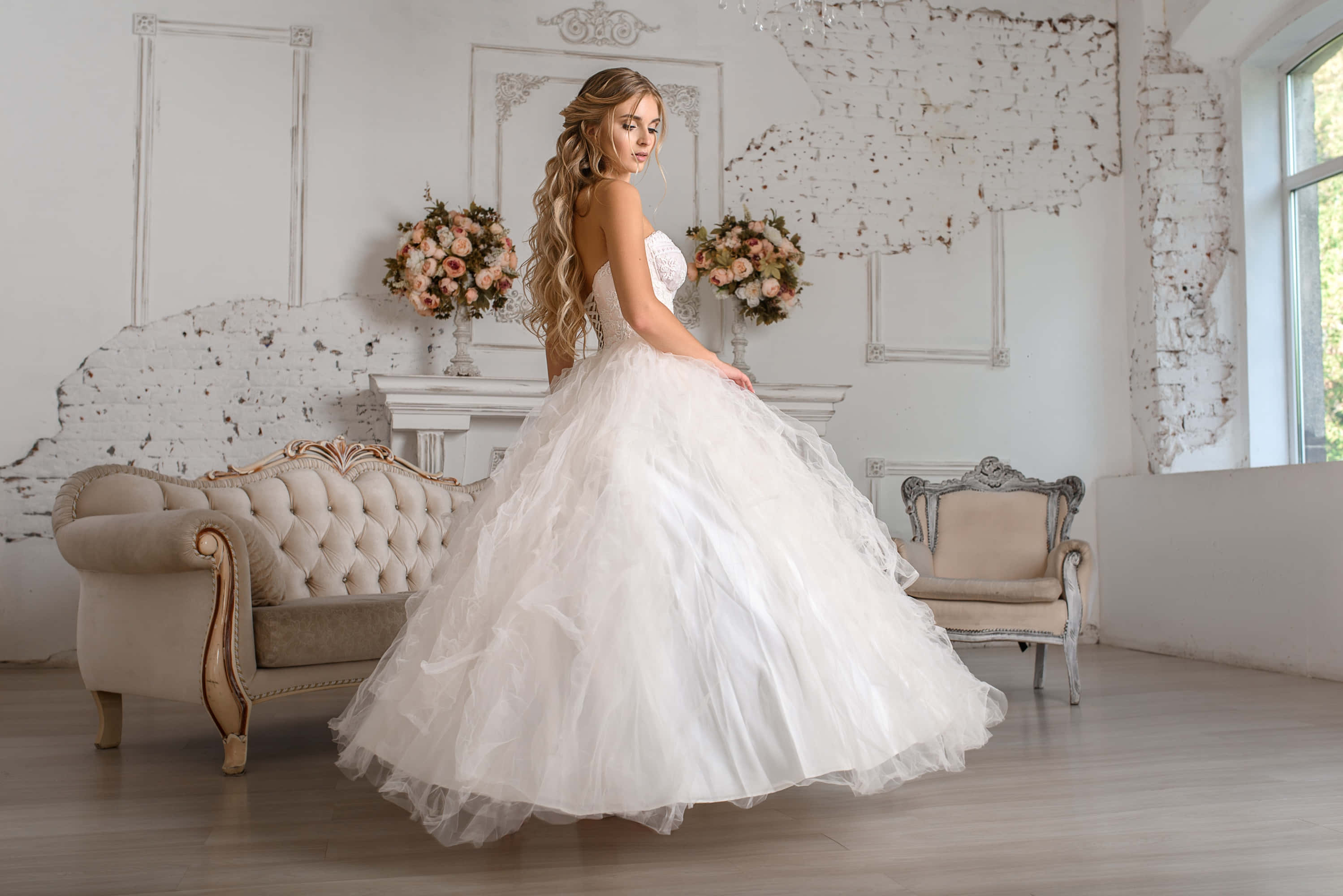 Wedding Dress 桌布 壁紙 — 一位身穿寬大白色婚紗的新娘，優雅地站在一個別緻的復古房間裡，房間有破舊的牆壁和花卉擺設。