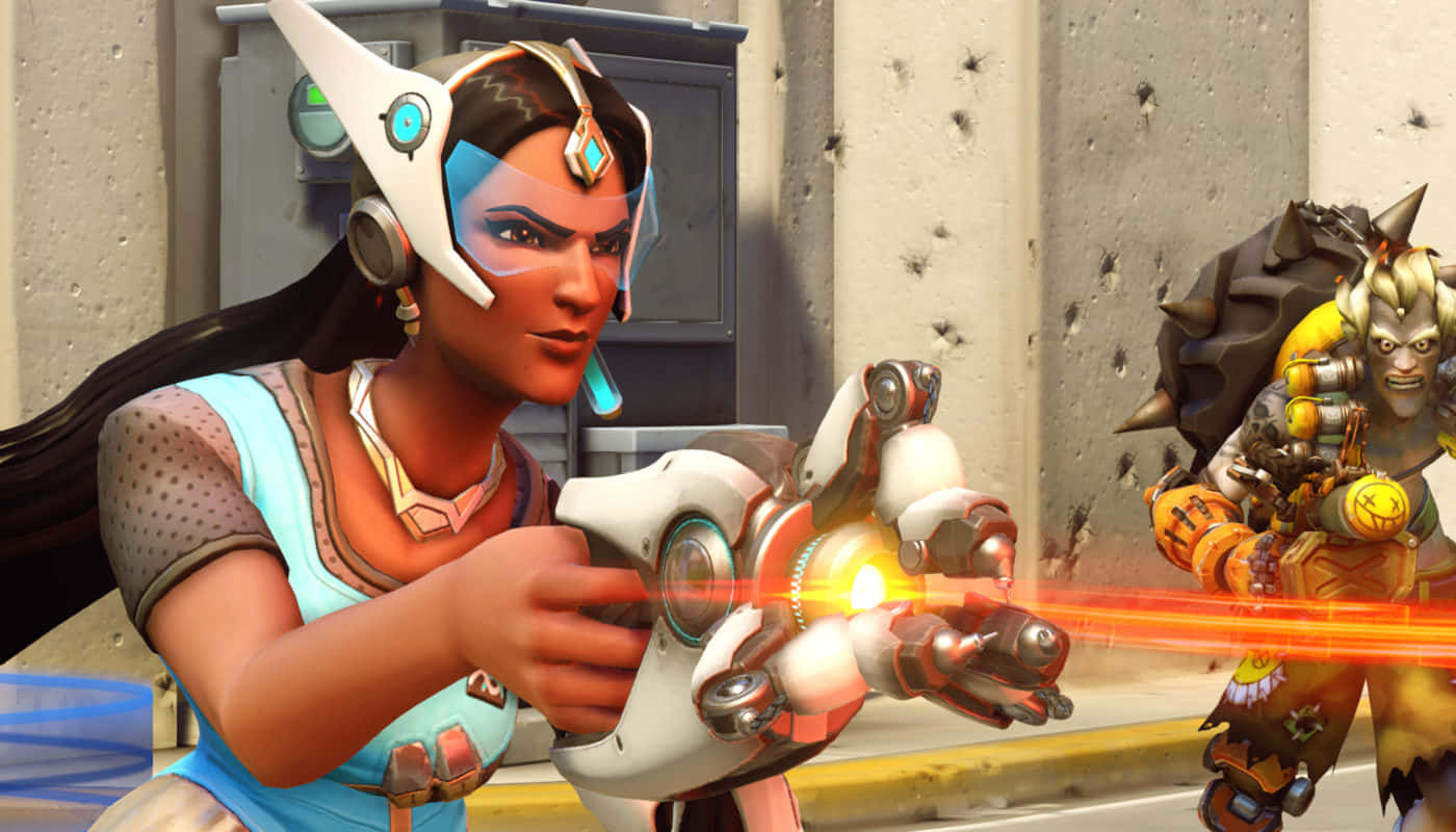 Overwatch Symmetra 桌布 壁紙 — 一位身穿未來裝甲的女英雄發射發光的橙色光束武器，而一位肌肉發達的戰士在她身後骯髒的城市小巷中準備就緒。