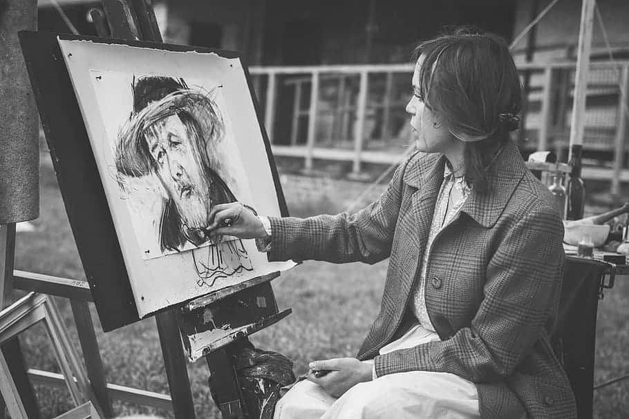Charcoal Drawings 桌布 壁紙 — 一位身穿格仔外套嘅女士喺戶外畫架上用黑白素描一幅肖像。
