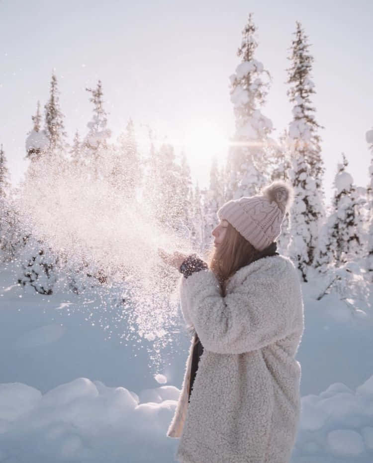 Winter Photography 桌布 壁紙 — 一位身穿毛絨白色外套和粉紅色冷帽的女性，在明亮的陽光冬日森林中拋雪。