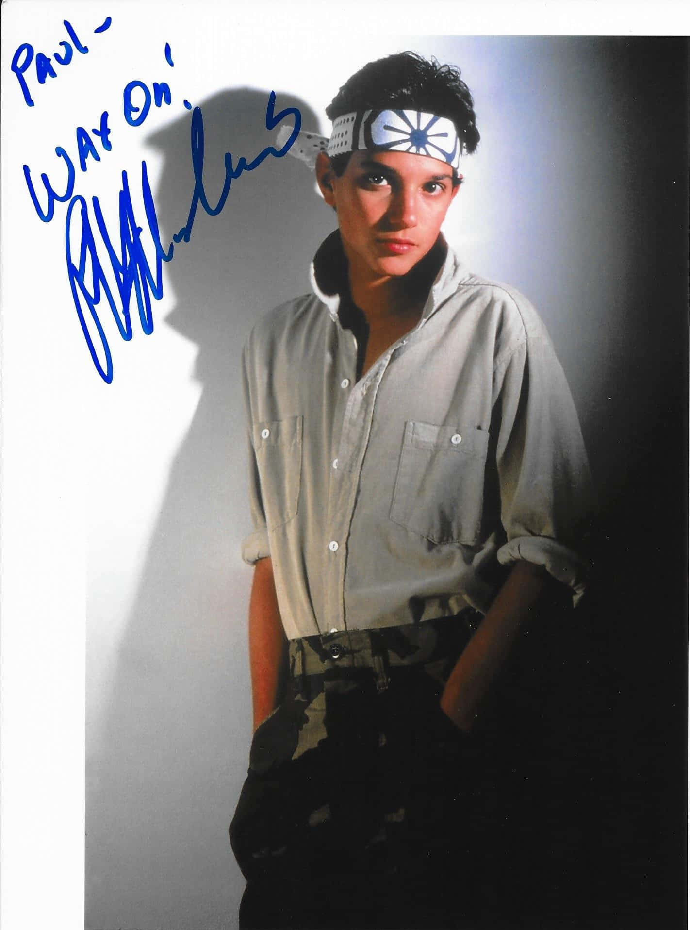 Ralph Macchio 桌布 壁紙 — 一位身穿淺色襯衫和頭帶的年輕男子，在純白背景前擺姿勢，搭配戲劇性燈光和手寫簽名。