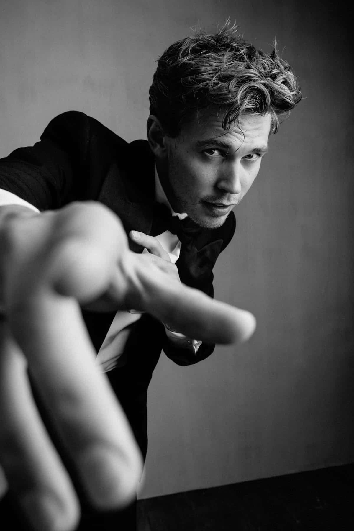 Black And White Celebrity 桌布 壁紙 — 一位身穿燕尾服的男人向前傾身，伸出手朝向觀看者，呈現戲劇性的黑白肖像。