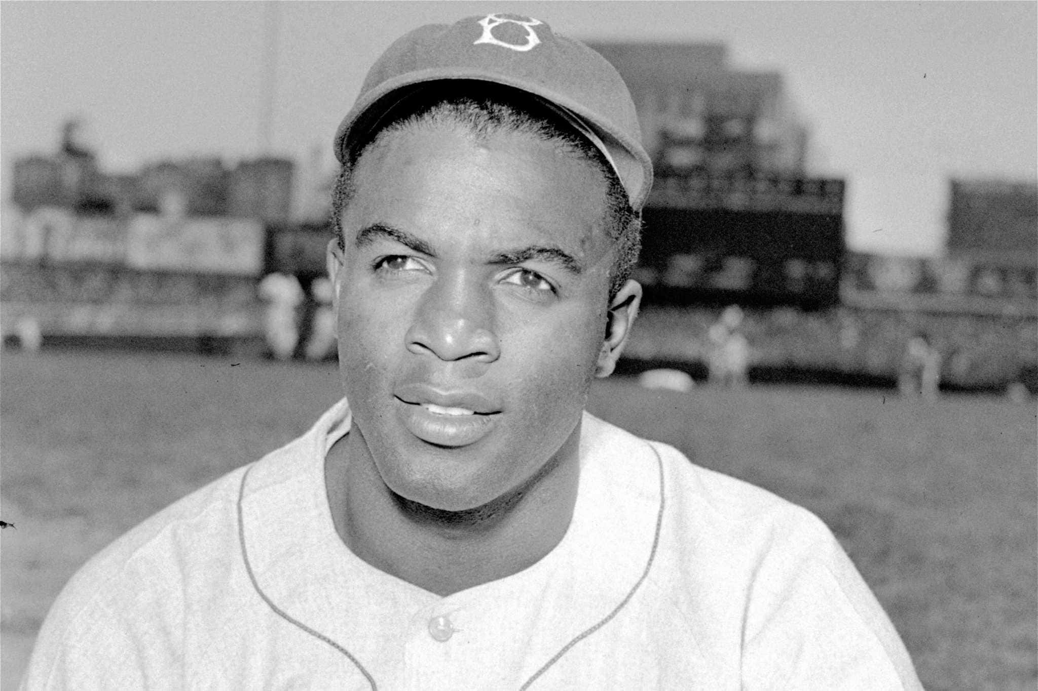 Jackie Robinson 桌布 壁紙 — 一位身穿球衣的棒球運動員的黑白肖像，目光離開鏡頭，背景是體育場。