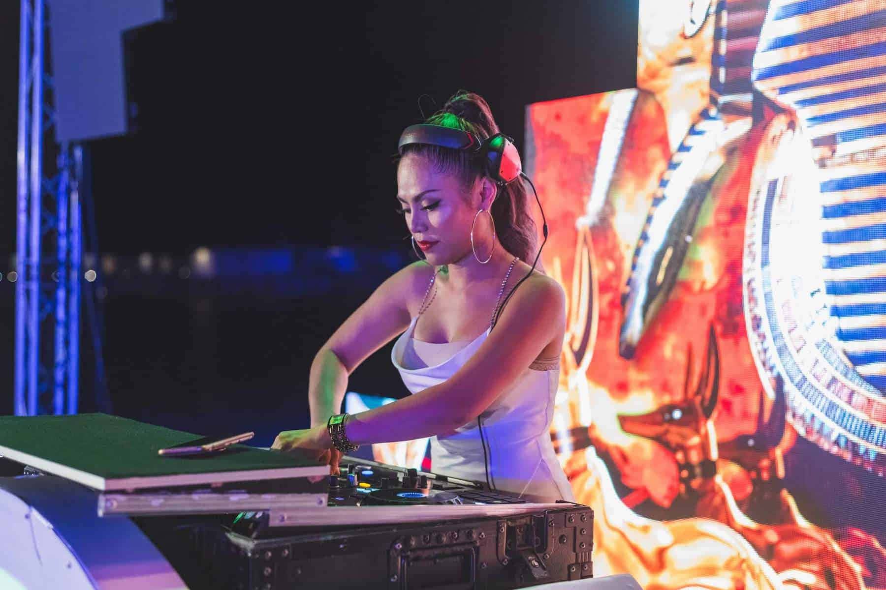 DJ 桌布 壁紙 — 一位身穿白色上衣、戴著耳機的女DJ，在充滿活力的舞台燈光下，以火焰動畫背景在唱盤上混音。