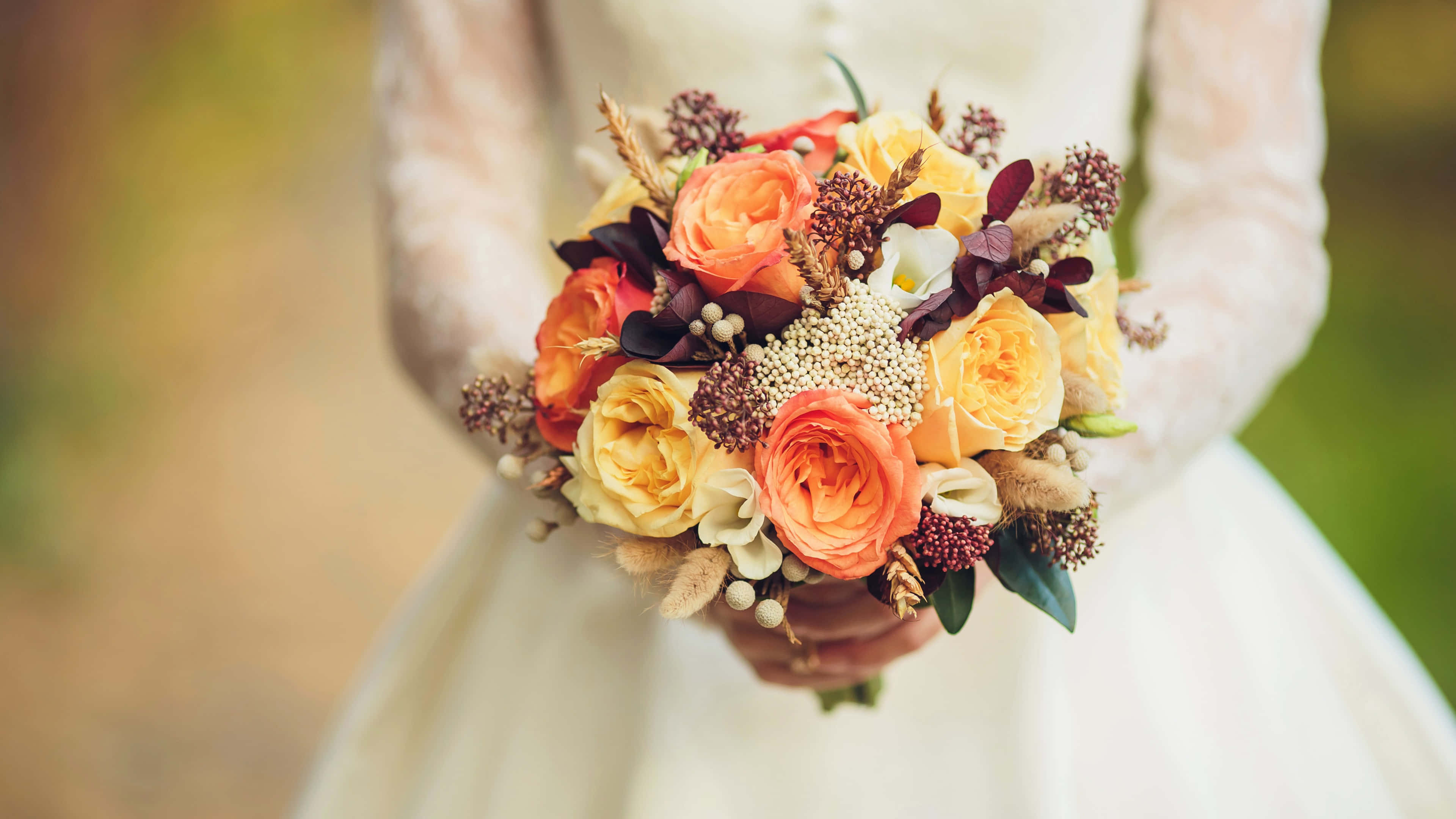 Wedding Bouquet 桌布 壁紙 — 一位身穿白色婚紗的新娘，在柔和模糊的背景前，手持一束充滿活力的橙黃色玫瑰和秋日點綴的花束。