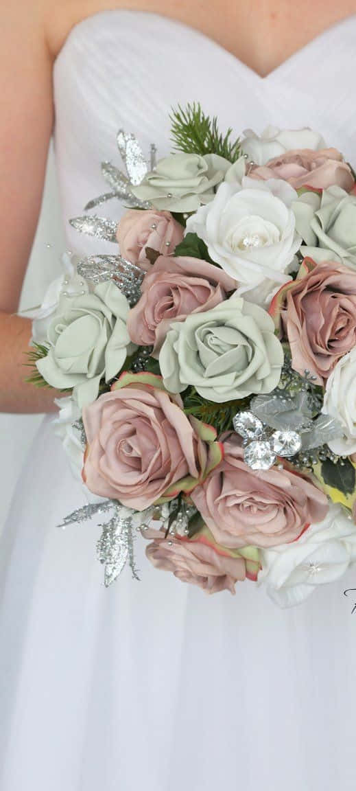Roses Wedding 桌布 壁紙 — 一位身穿白色婚紗的新娘手持一束豐滿的淡粉紅色和鼠尾草綠色玫瑰，點綴著銀色閃粉葉子和松針。