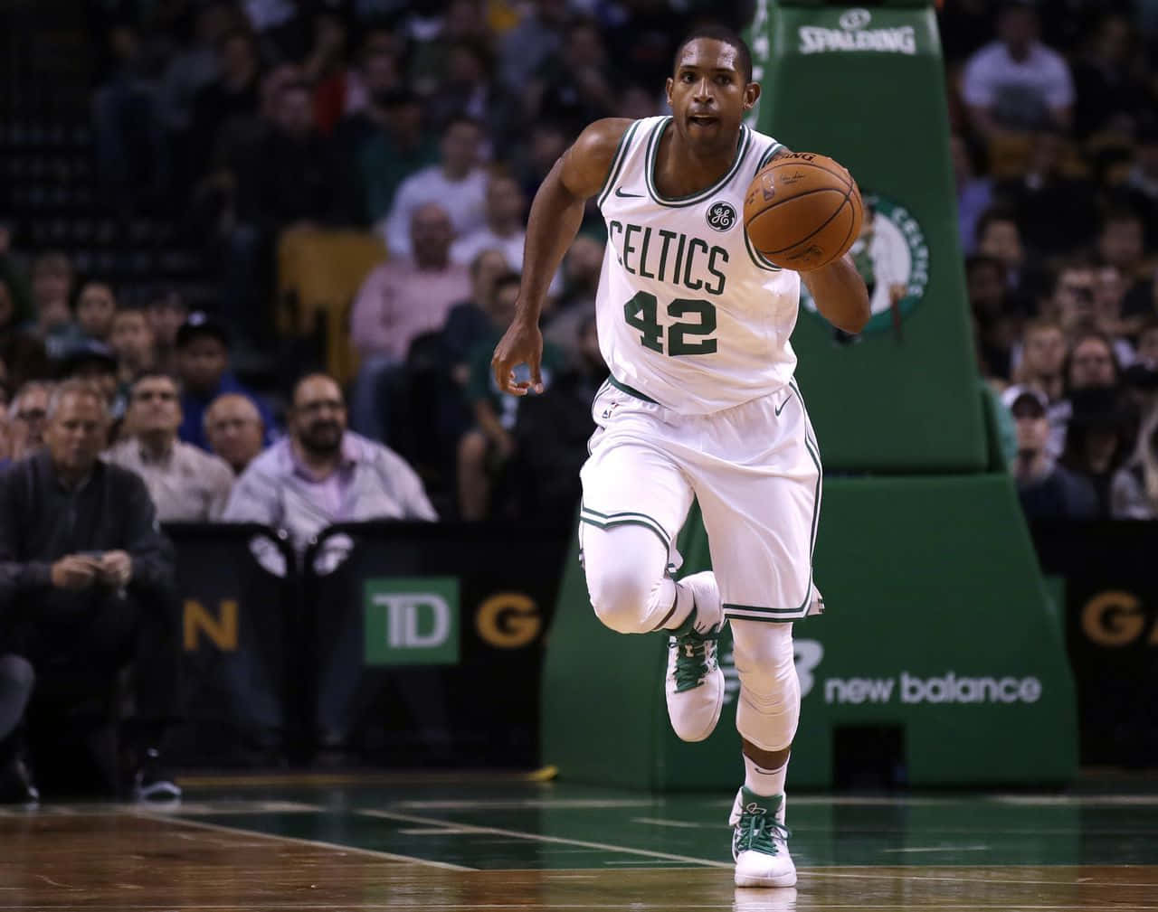 Al Horford 桌布 壁紙 — 一位身穿白色球衣、背號42的波士頓塞爾特人籃球運動員，在滿場觀眾的背景下，於一場激烈的比賽中運球。