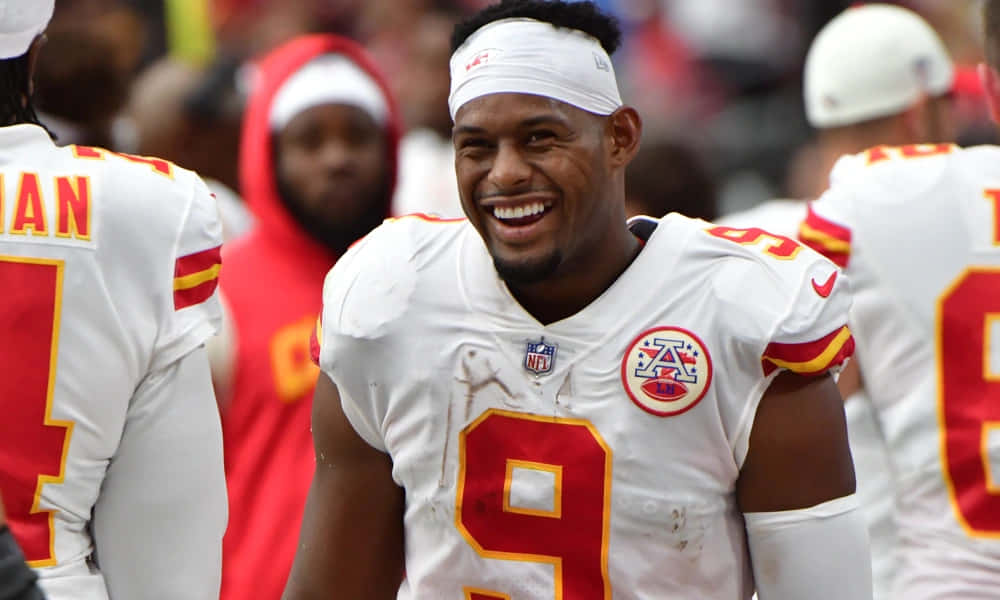 Juju Smith Schuster 桌布 壁紙 — 一位身穿白色球衣、背號9號的足球運動員在比賽中開懷大笑。