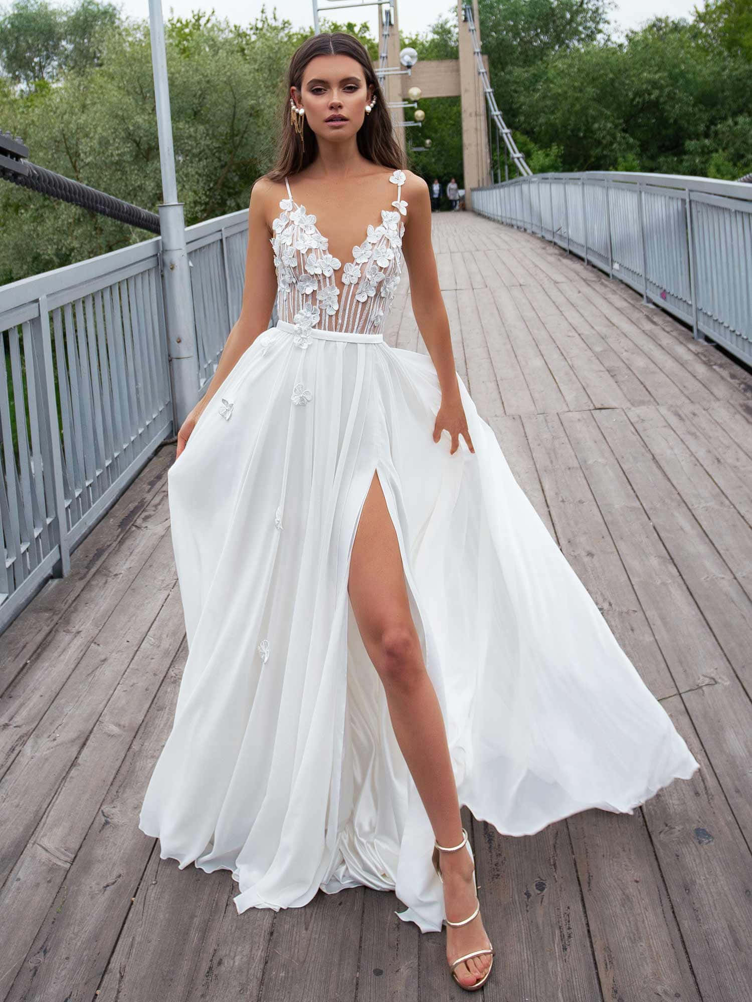 Wedding Dress 桌布 壁紙 — 一位身穿白色花卉長裙的女性，優雅地站在一座被茂密綠樹環繞的木製行人橋上。
