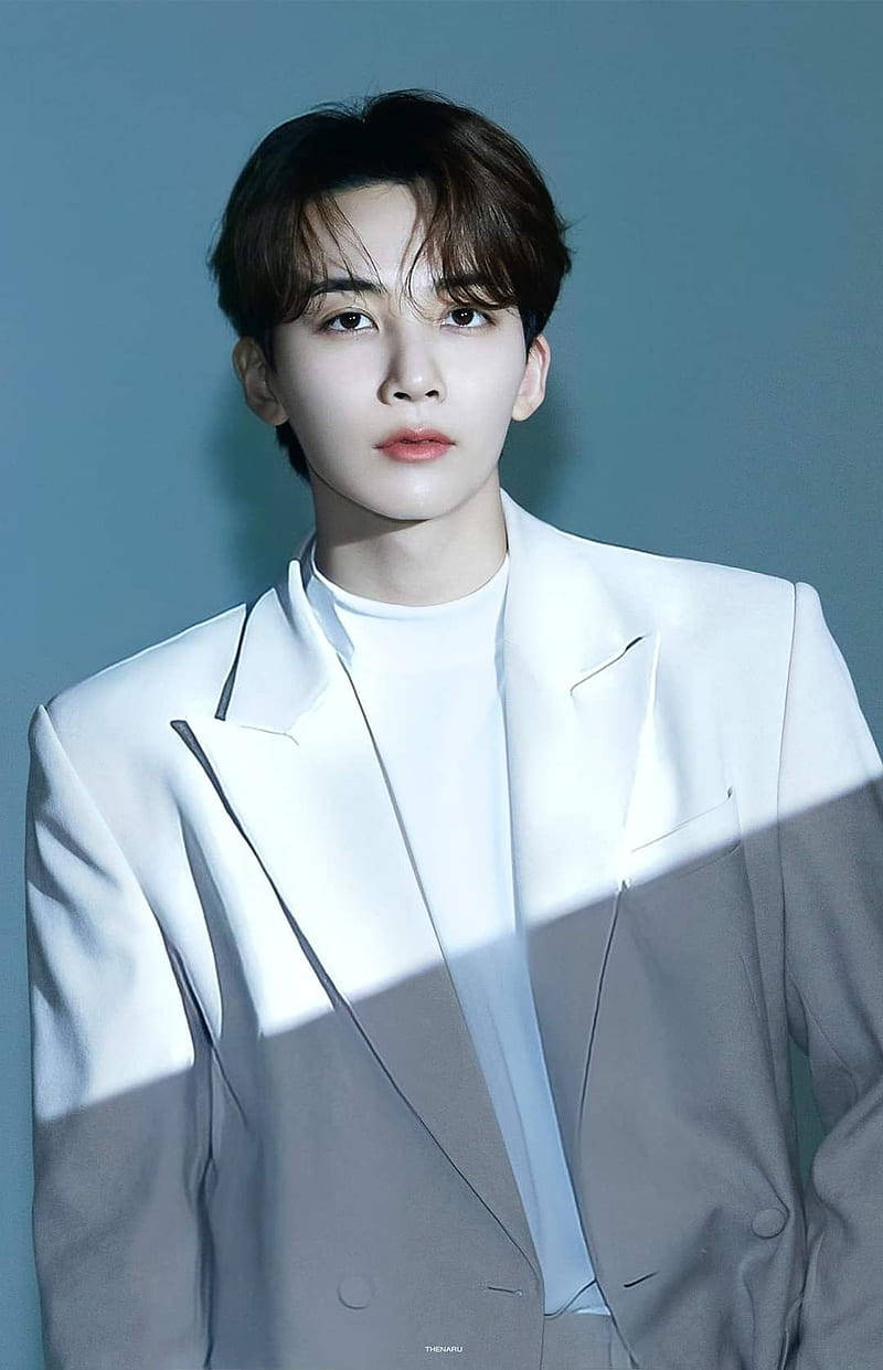 Yoon Jeonghan IN-COMPLETE 壁紙 — 一位身穿白色西裝的年輕男子站在清涼的藍色背景前，戲劇性的燈光在他的軀幹上投下銳利的陰影。