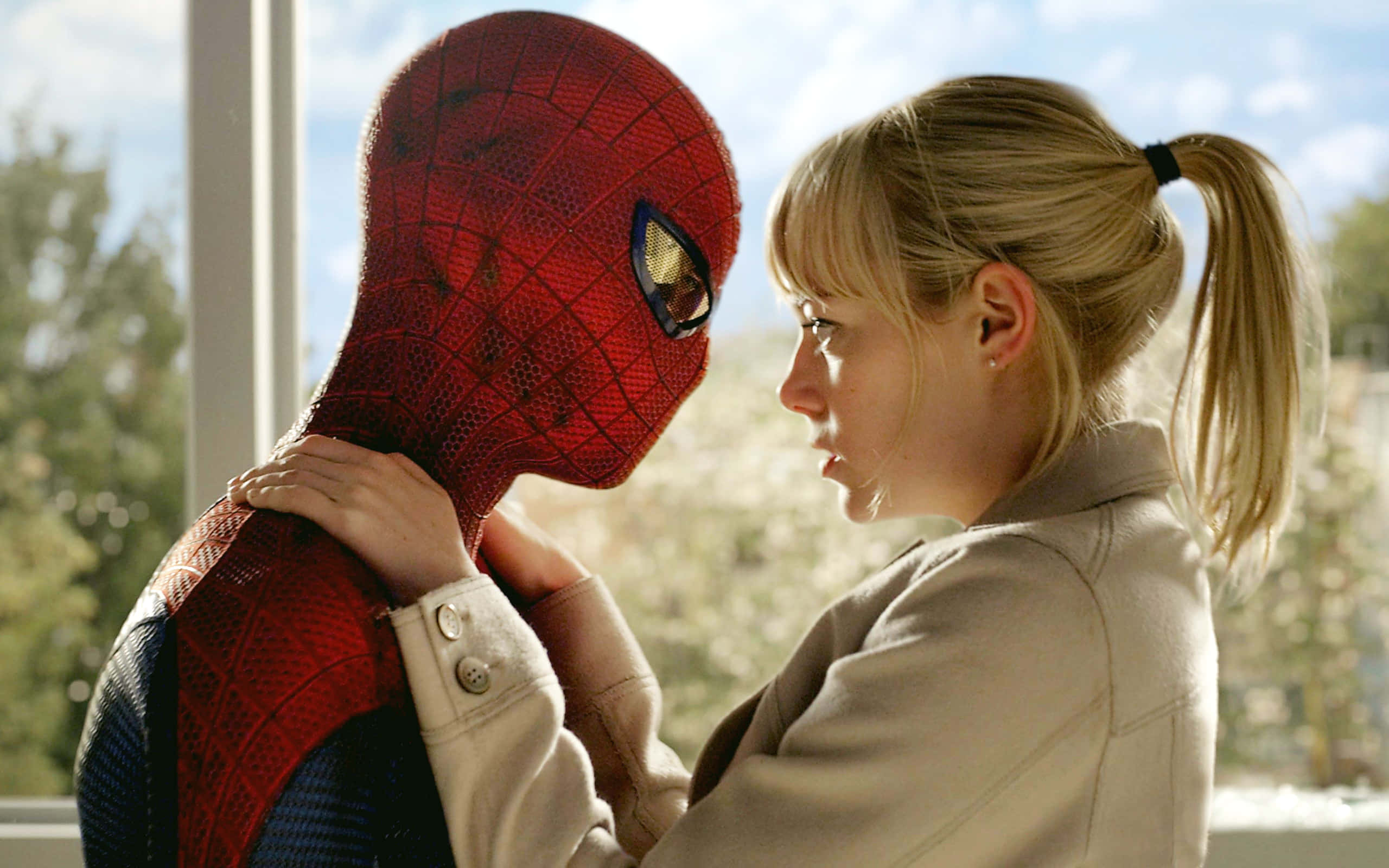 Gwen Stacy 桌布 壁紙 — 一位身穿米色外套的女性輕輕地扶著蜘蛛俠的肩膀，他們在明亮的窗邊面對面。