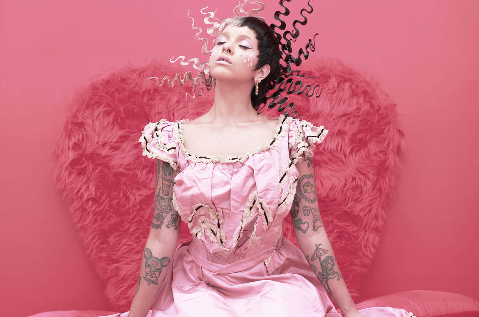 Melanie Martinez 桌布 壁紙 — 一位身穿粉紅色緞面連衣裙、帶有紋身的女性，坐在一個蓬鬆的粉紅色心形背景前，背景中有旋轉的黑白煙霧。
