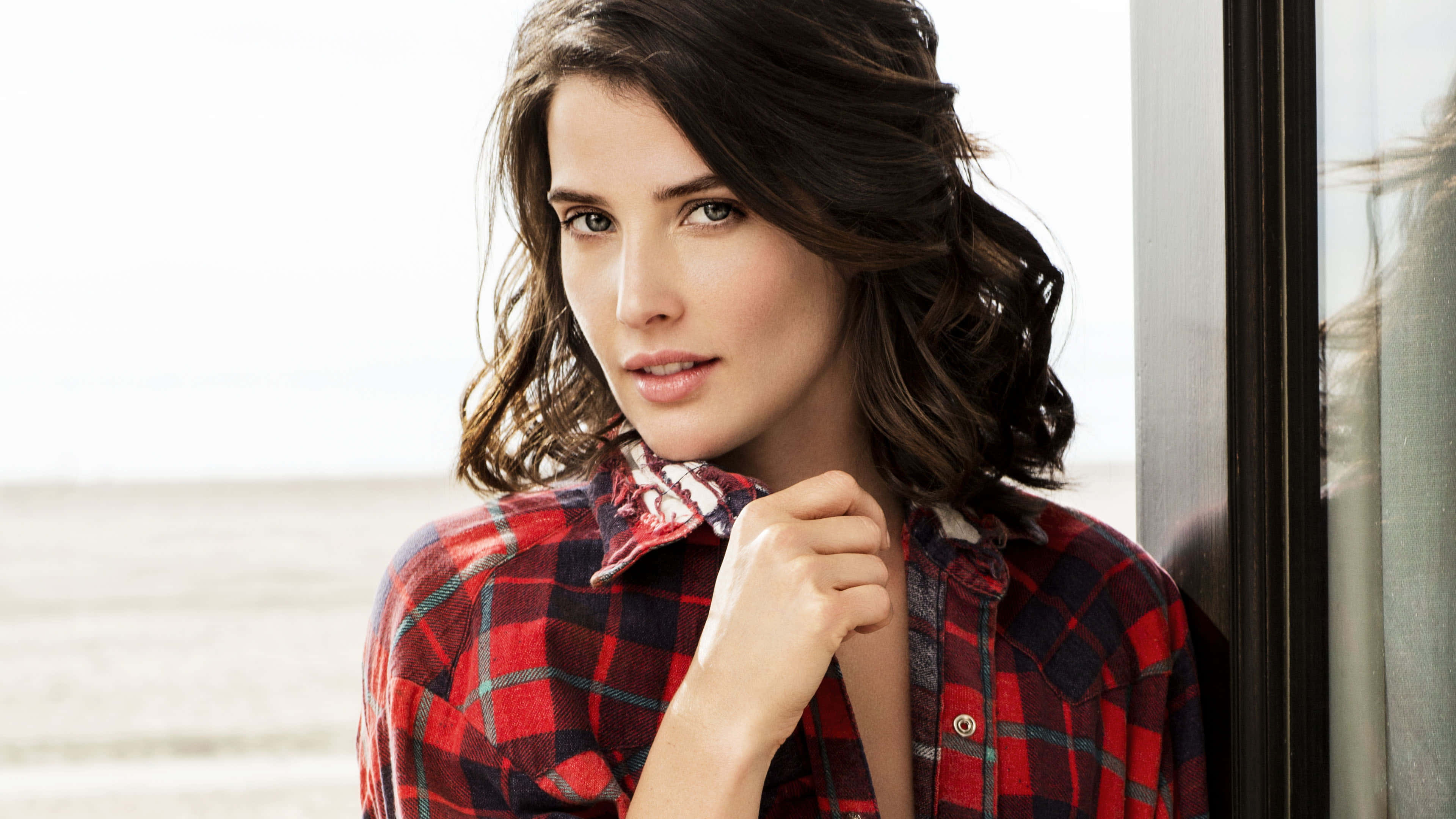 Cobie Smulders 桌布 壁紙 — 一位身穿紅色格仔恤衫嘅女人挨喺窗邊，背景係模糊嘅沙灘。
