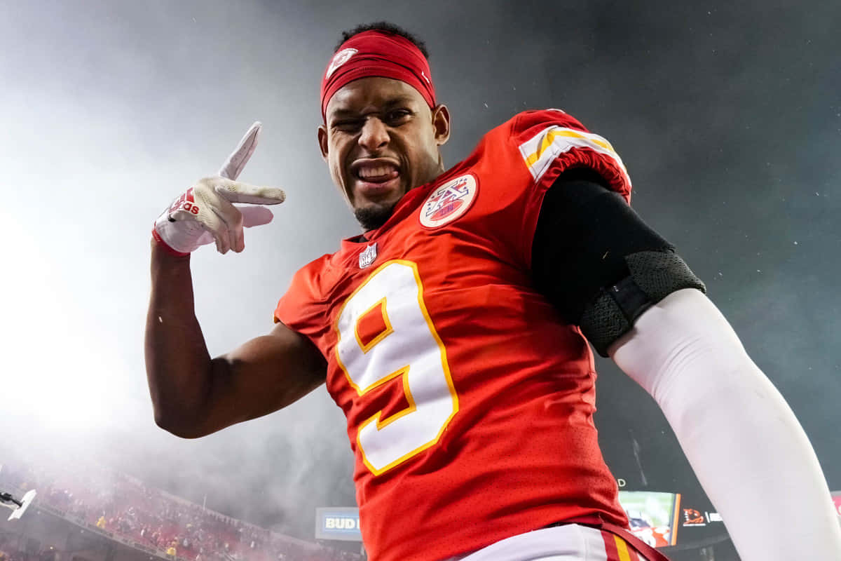 Juju Smith Schuster 桌布 壁紙 — 一位身穿紅色球衣、背號九號的足球運動員在明亮的燈光下於球場上熱情慶祝。