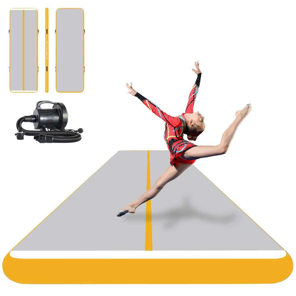 Gymnastics Mat 桌布 壁紙 — 一位身穿紅色緊身衣的年輕體操運動員在灰色和黃色的充氣體操墊上做出動態的劈叉跳躍動作，附近顯示有泵。
