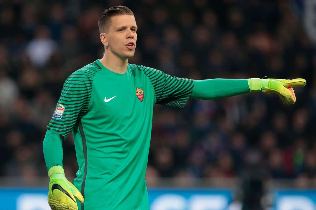 Wojciech Szczesny 桌布 壁紙 — 一位身穿綠色球衣的專注足球守門員在夜間比賽中以指向手勢指揮隊友。