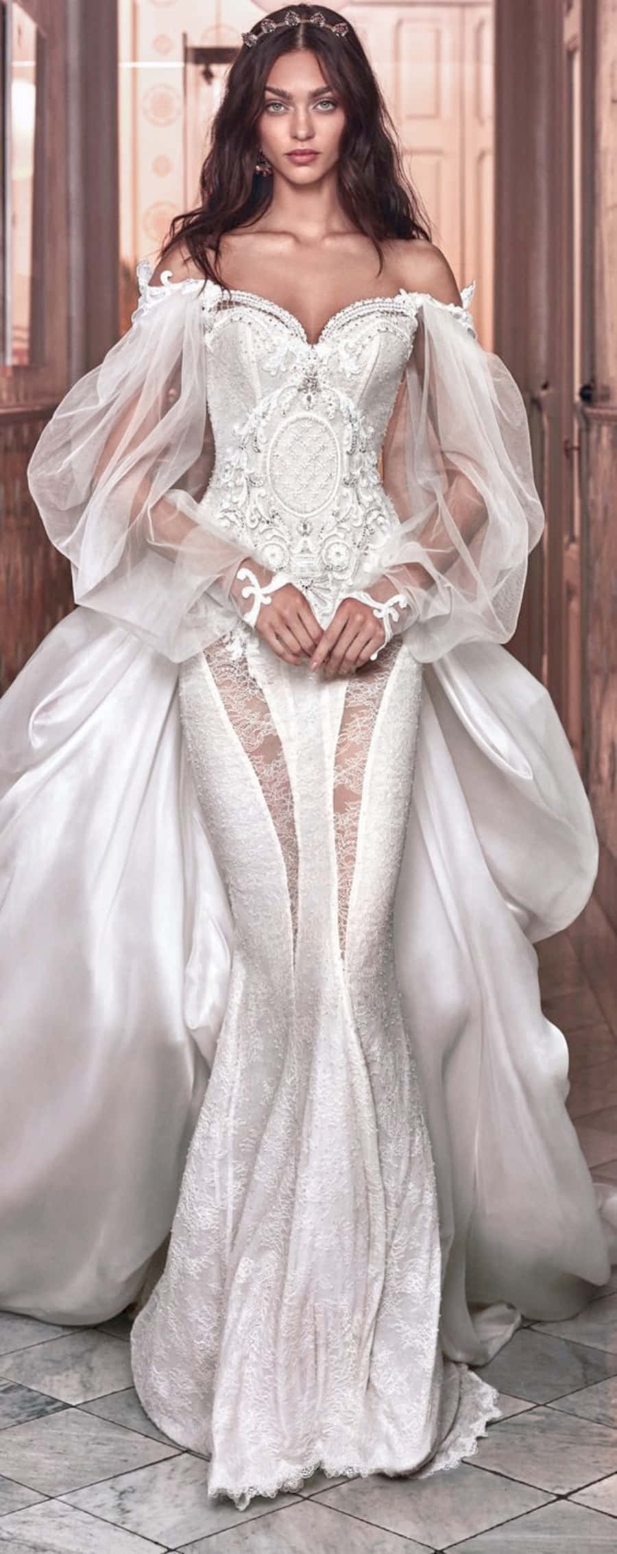 Wedding Dress 桌布 壁紙 — 一位身穿華麗白色婚紗、帶有透明泡泡袖和蕾絲細節的女性，在溫暖燈光的木質房間裡擺姿勢。