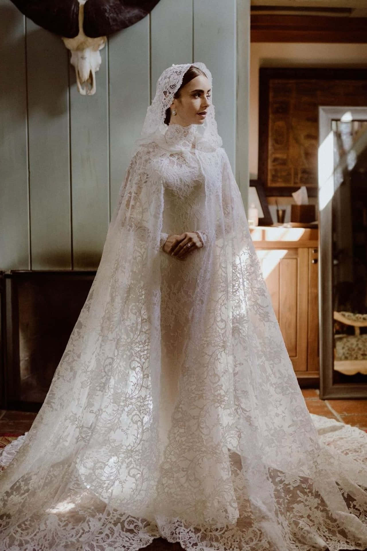 Bride's Dress 桌布 壁紙 — 一位身穿華麗白色蕾絲婚紗、披著飄逸頭紗的女性，站在一個沐浴在柔和陽光下的質樸木屋中。