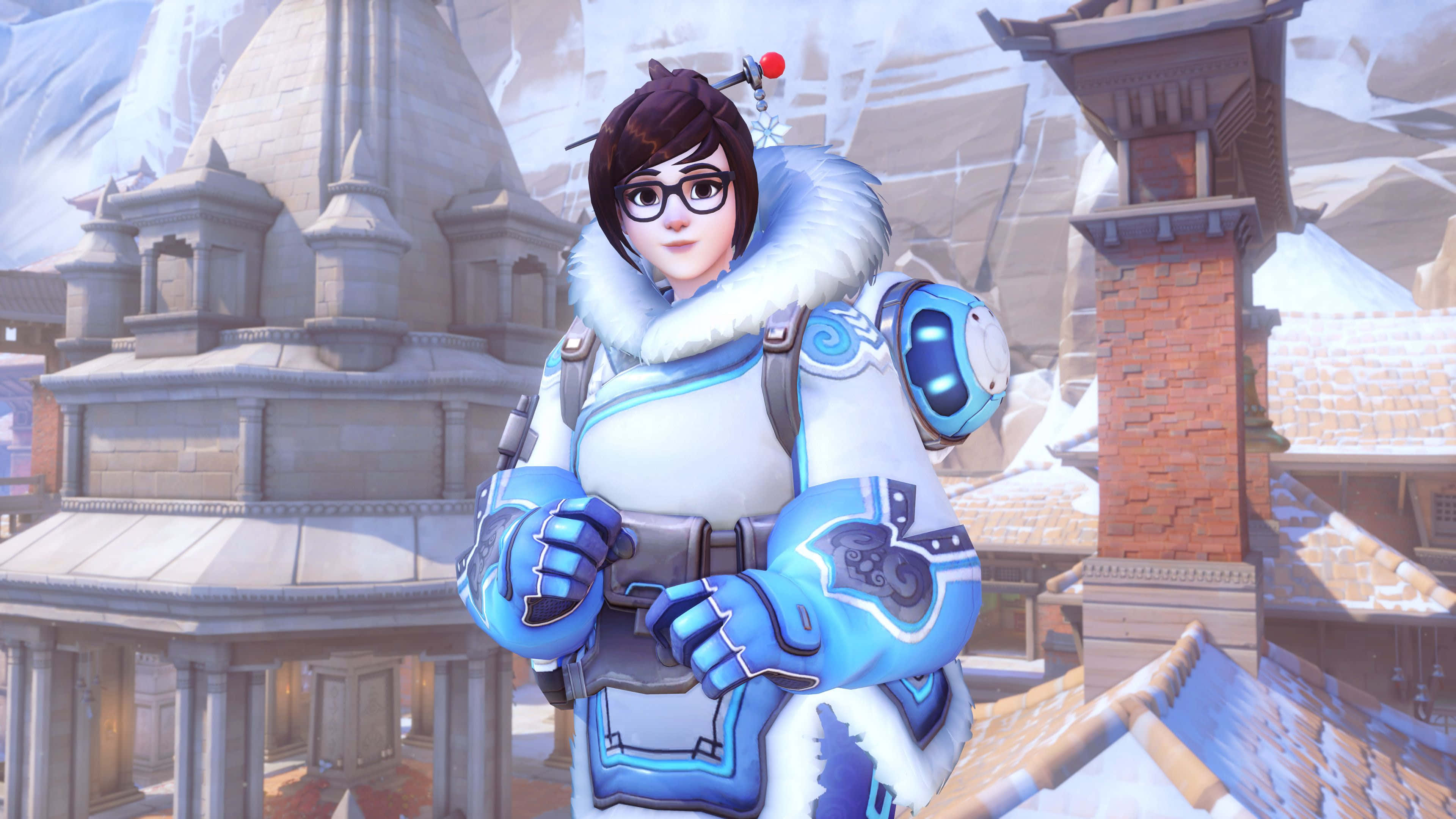 Overwatch Mei 桌布 壁紙 — 一位身穿藍白冬季裝備的女性英雄自信地站在一個有石頭建築和積雪屋頂的雪村中。